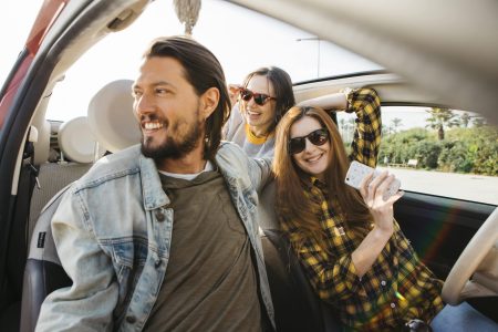 smiling-woman-with-smartphone-positive-man-car-near-lady-leaning-out-from-auto-min smiling-woman-with-smartphone-positive-man-car-near-lady-leaning-out-from-auto-min